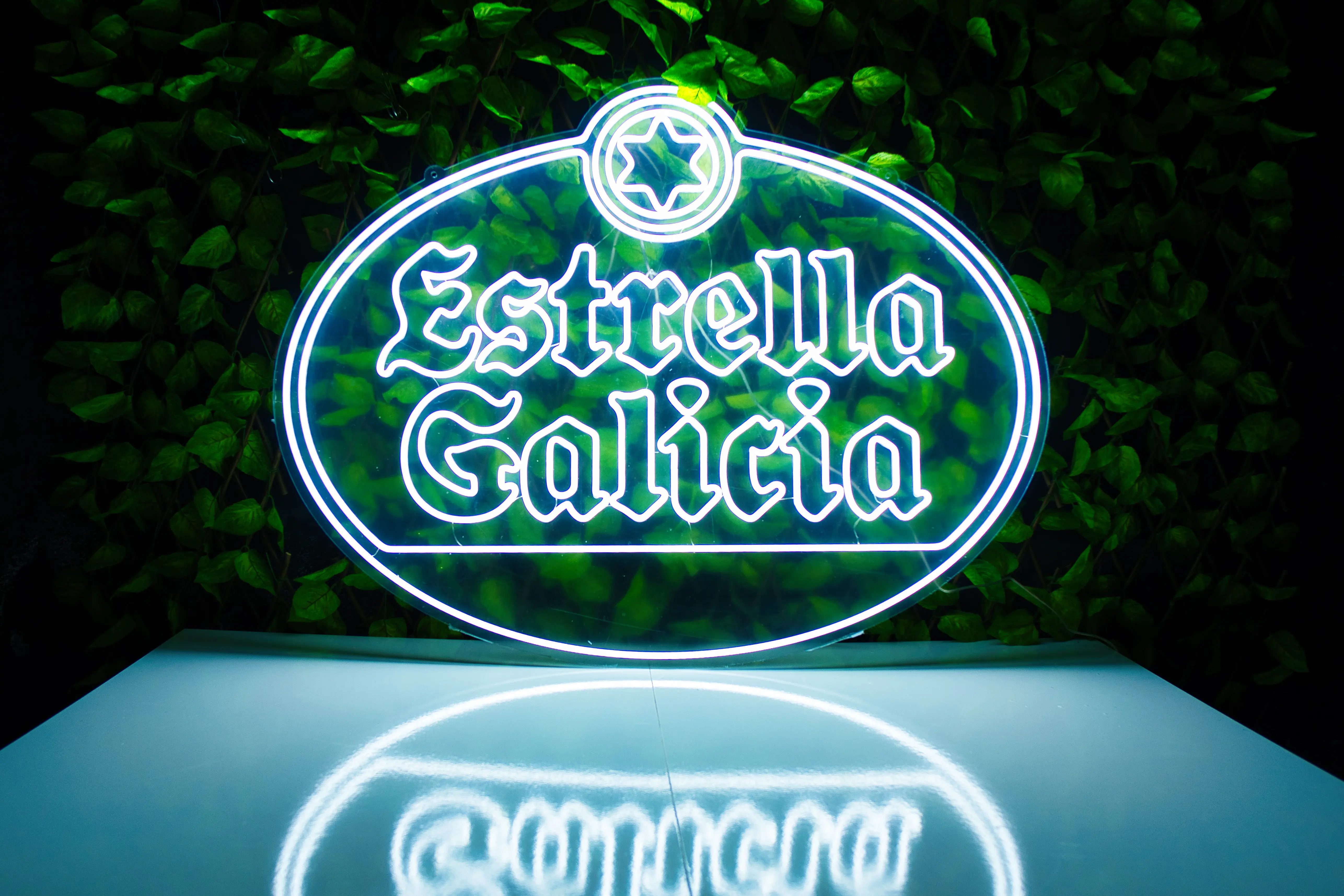 Logo néon personnalisé pour Estrella Galicia sur un mur végétal