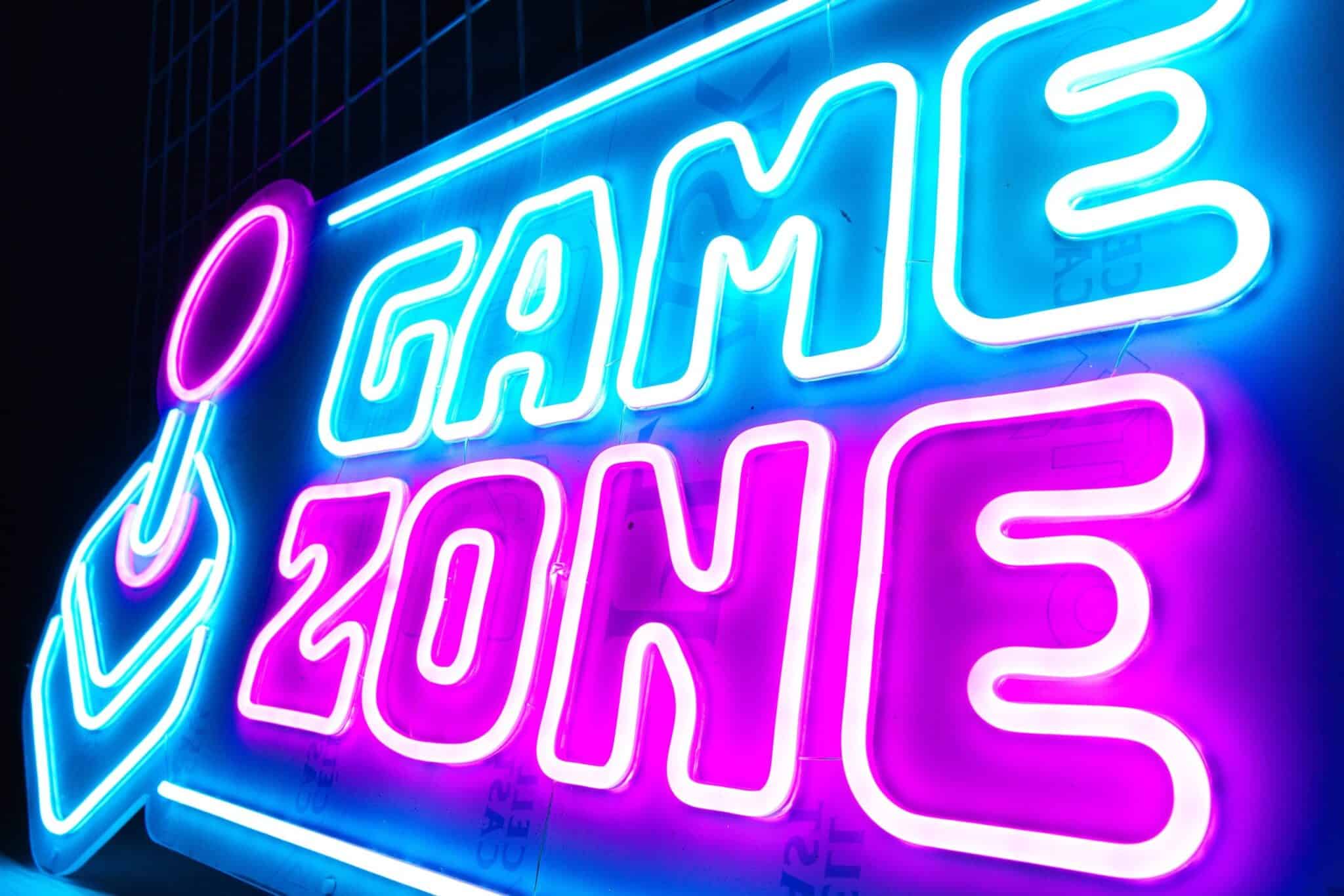 Letrero de neón que muestra las palabras "zona de juego" en colores azul y rosa brillantes.