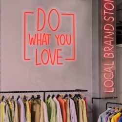 The Neon Sign: Do What You Love hangs above a clothing rack with assorted shirts in a retail store.