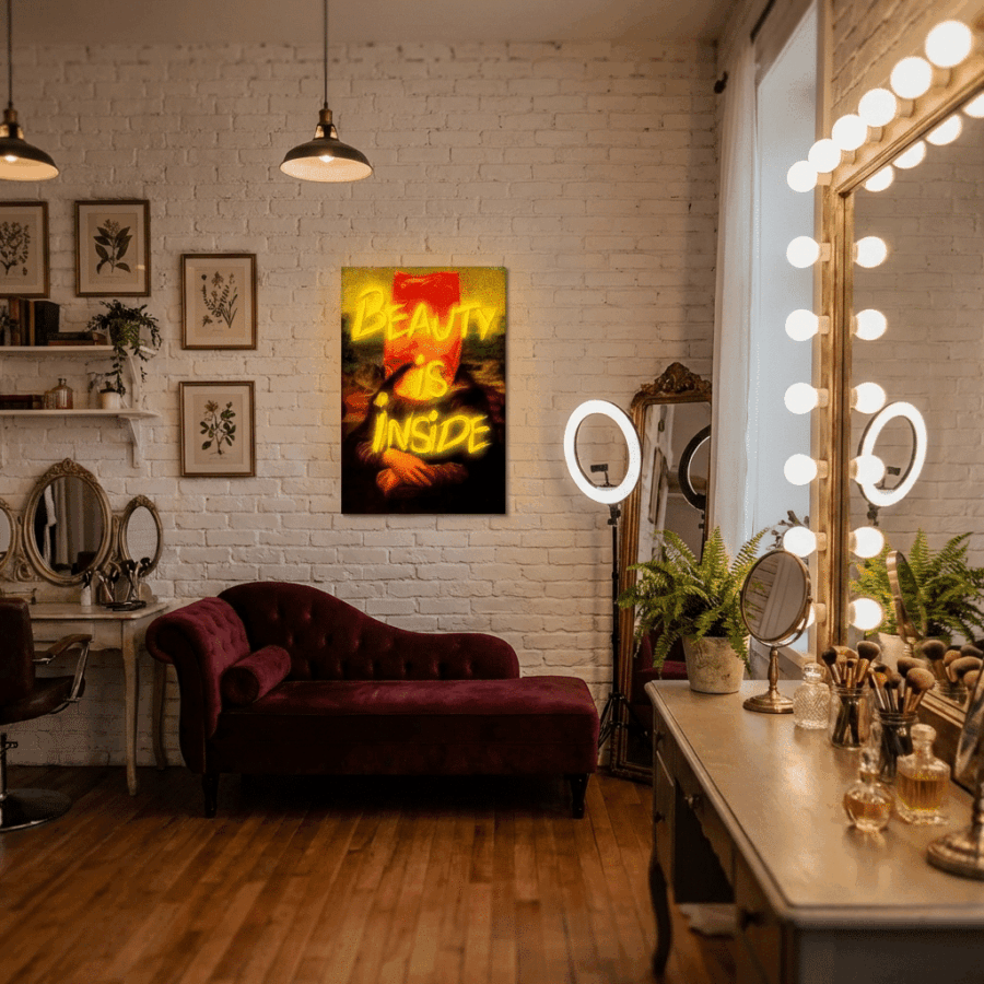 A makeup studio featuring a vanity mirror with lights, a velvet chaise lounge, wall art, and the Neon Sign Beauty is Inside.