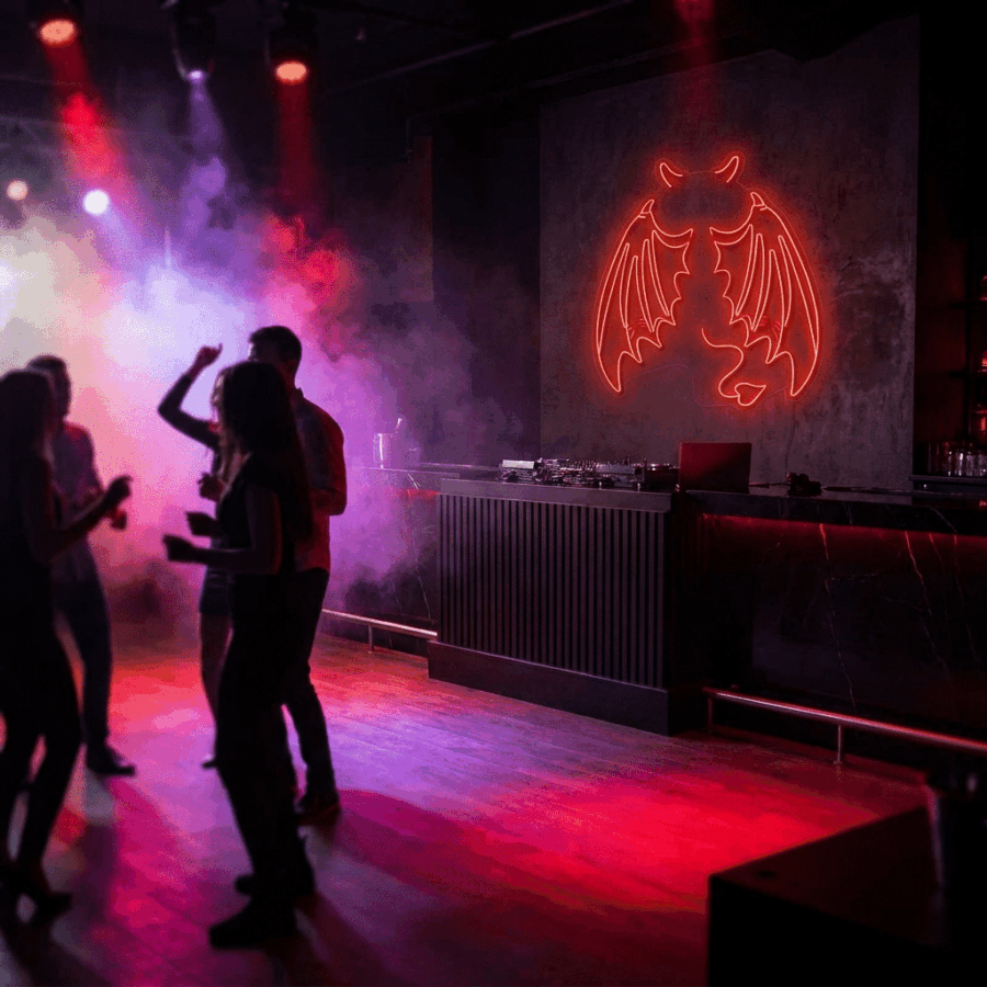 People dance in a dimly lit nightclub with red lights, fog, and the Demon Wings Neon glowing above the DJ booth.