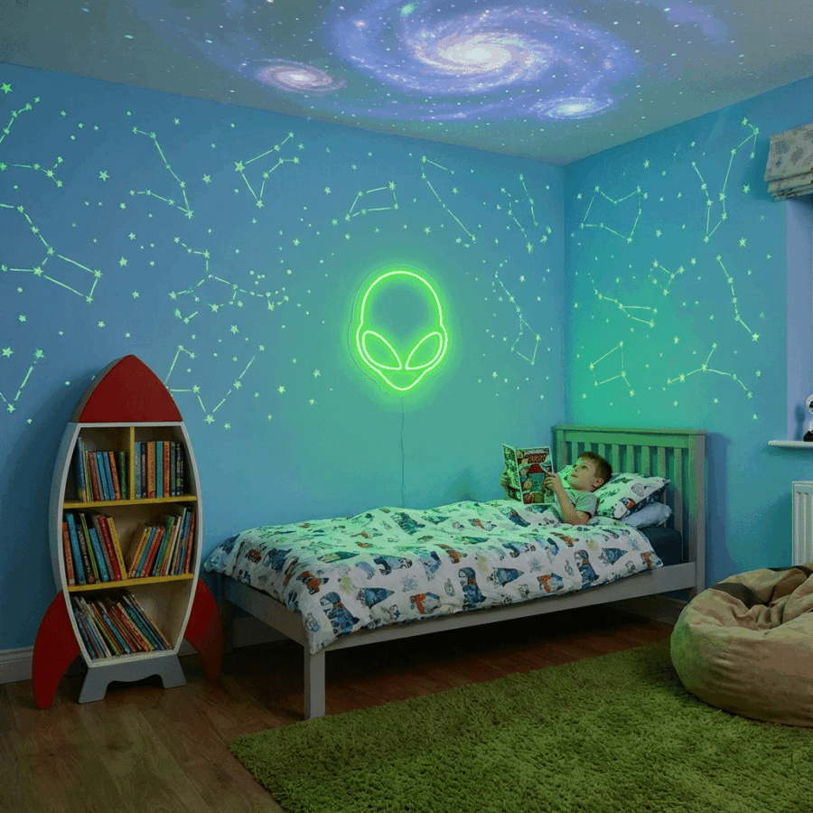 A child reads in a space-themed bedroom with constellation wall art, the Alien Neon light above the bed, a rocket-shaped bookshelf, and swirling galaxy projections illuminating the ceiling.