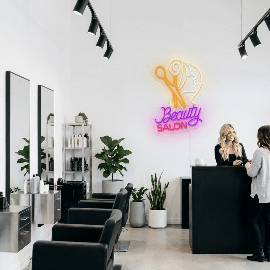 Inside the modern salon, black chairs, mirrors, and potted plants complement a Neon Beauty Salon sign as two women chat at the sleek black reception counter.