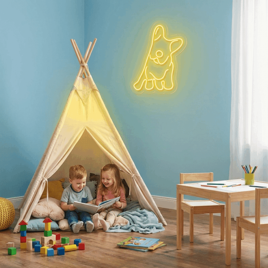 Two children sit inside a teepee reading a book. Above them, the French Bulldog Neon sign glows on the wall.