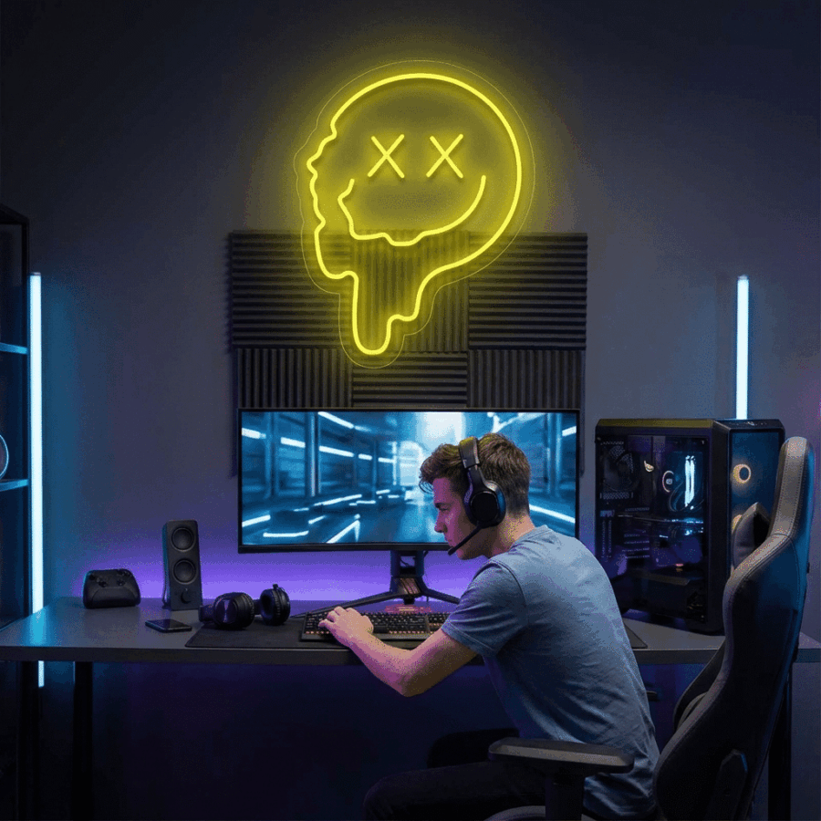 A person wearing a headset sits at a gaming desk with a monitor, keyboard, and PC; above them, the Smiling Face Neon sign glows yellow on the wall.