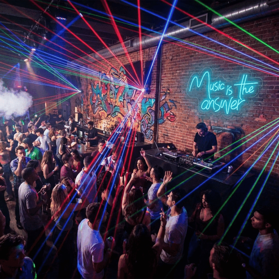 A crowded nightclub pulses with vibrant energy as a DJ spins tracks, colorful lasers flash, and the Neon Music is the Answer sign glows against the brick wall.