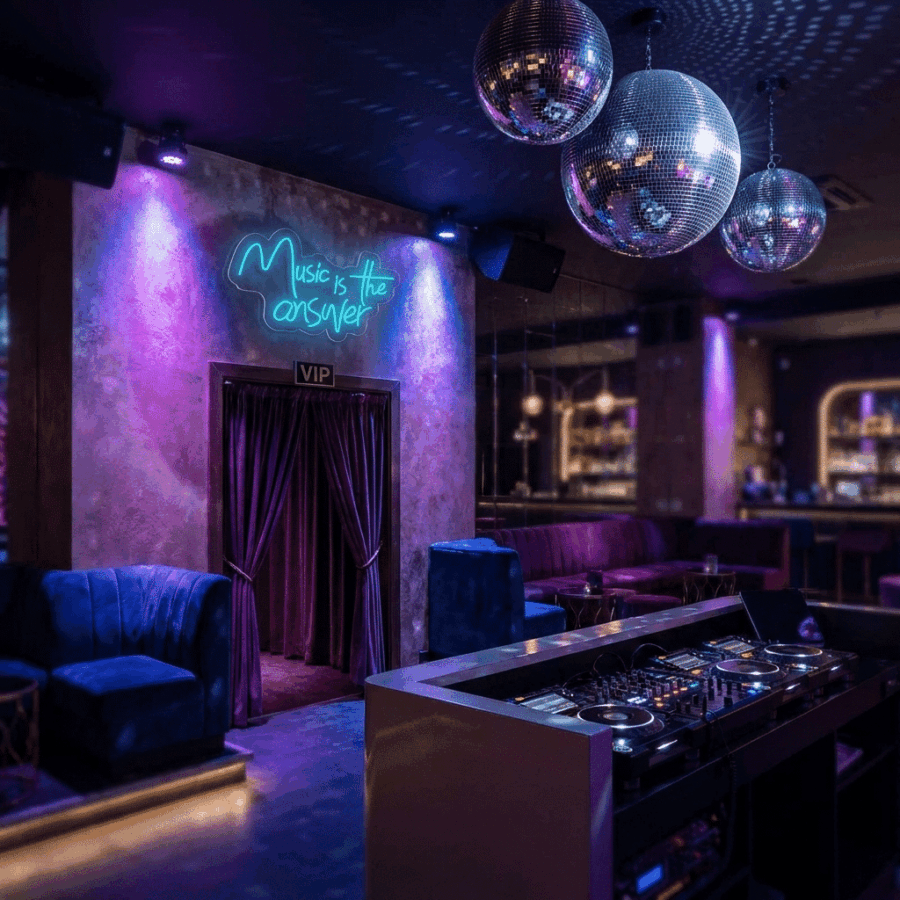 A nightclub interior features purple lighting, disco balls, a DJ booth, lounge seating, and the Neon Music is the Answer sign for a vibrant backdrop to your night out.