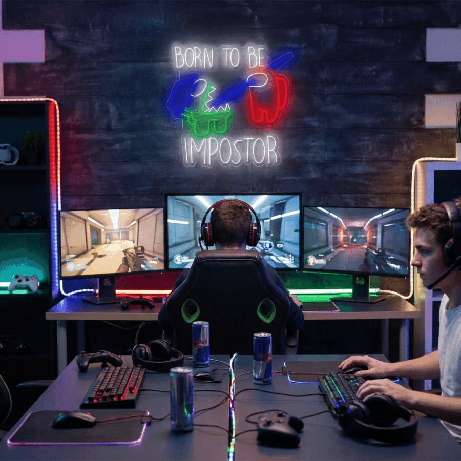 Two people play video games at desks with multiple monitors and LED lighting; the Neon Neon Among us sign glows above, displaying "BORN TO BE IMPOSTOR" alongside Among Us characters.