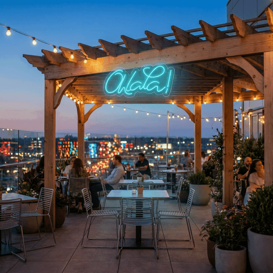 Diners enjoy a rooftop restaurant under a wooden pergola, illuminated by the Neon Ohlala! sign and surrounded by city lights in the evening.