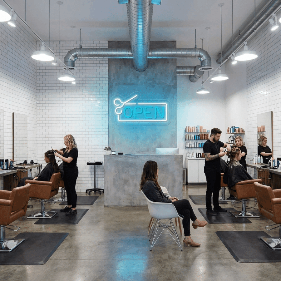 The Open Hair Salon Neon glows above the front desk of a modern salon, where expert stylists work on clients. Premium hair products fill the shelves, creating a vibrant and welcoming atmosphere.