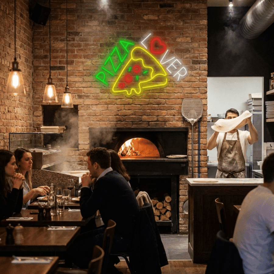 A chef prepares pizza dough near a wood-fired oven beneath the glowing Neon Pizza Lover sign, as diners enjoy their meals at tables in the foreground.
