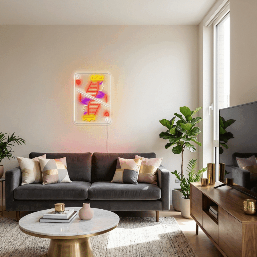 Modern living room with a gray sofa, pastel pillows, potted plants, a round coffee table, and the Neon Q hearts sign displayed above the sofa.
