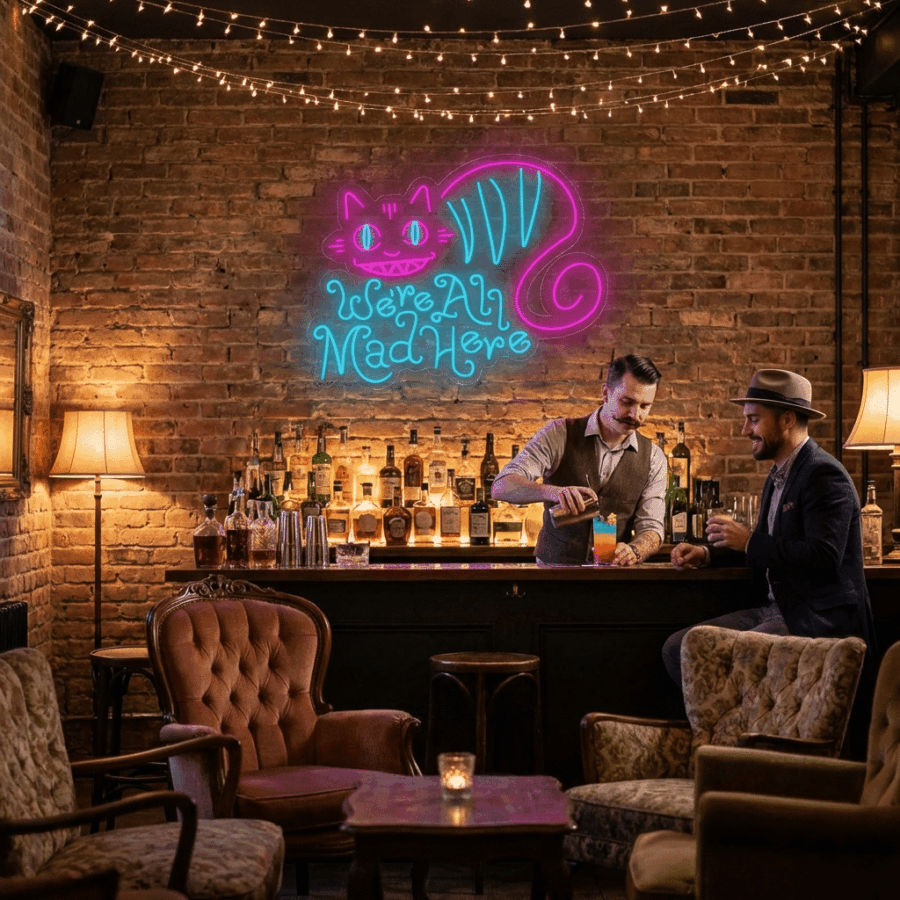 Two men at a cozy bar with vintage decor; one serves a colorful drink. Behind them, a Neon We're all mad here sign glows on the brick wall.